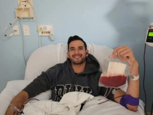 Ari Sohn seated in the donor chair holding his donated stem cells